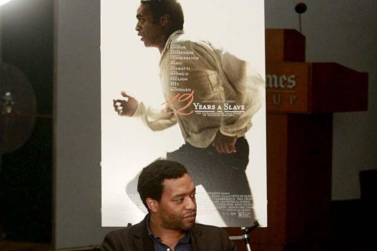 Chiwetel Ejiofor, star of "12 Years a Slave," chats about the film, with its U.S poster behind him. On the film's Italian posters, however, his image is dwarfed by those of white actors who play less prominent roles.