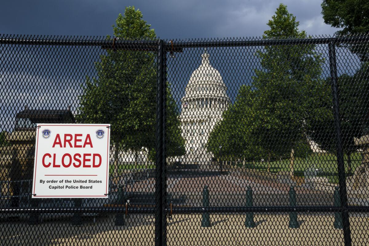 The U.S. Capitol is seen under dark skies in Washington, Tuesday, June 8, 2021, as barriers remain six months after the Jan. 6 attack. A Senate report examining security failures surrounding the Jan. 6 insurrection at the U.S. Capitol blames missed intelligence, poor planning and multiple layers of bureaucracy for the deadly siege. (AP Photo/J. Scott Applewhite)