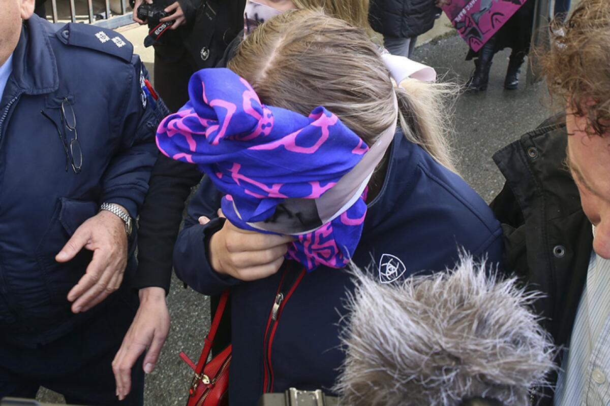 A British woman shields her face as she leaves a courthouse in Paralimni, Cyprus, on Monday. The 19-year-old, who has not been identified, was found guilty of the charge of “public mischief.”