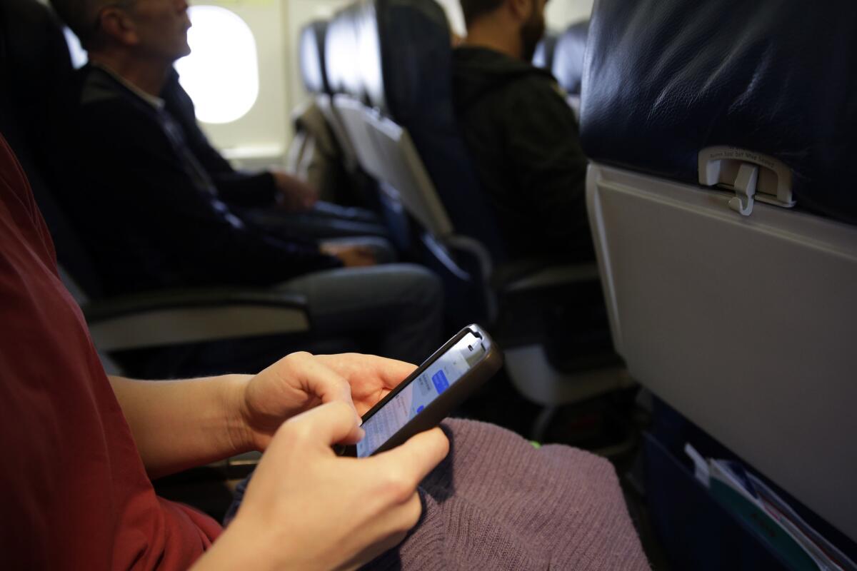 A passenger checks her cellphone after boarding a flight in Boston on Oct. 31, 2013.