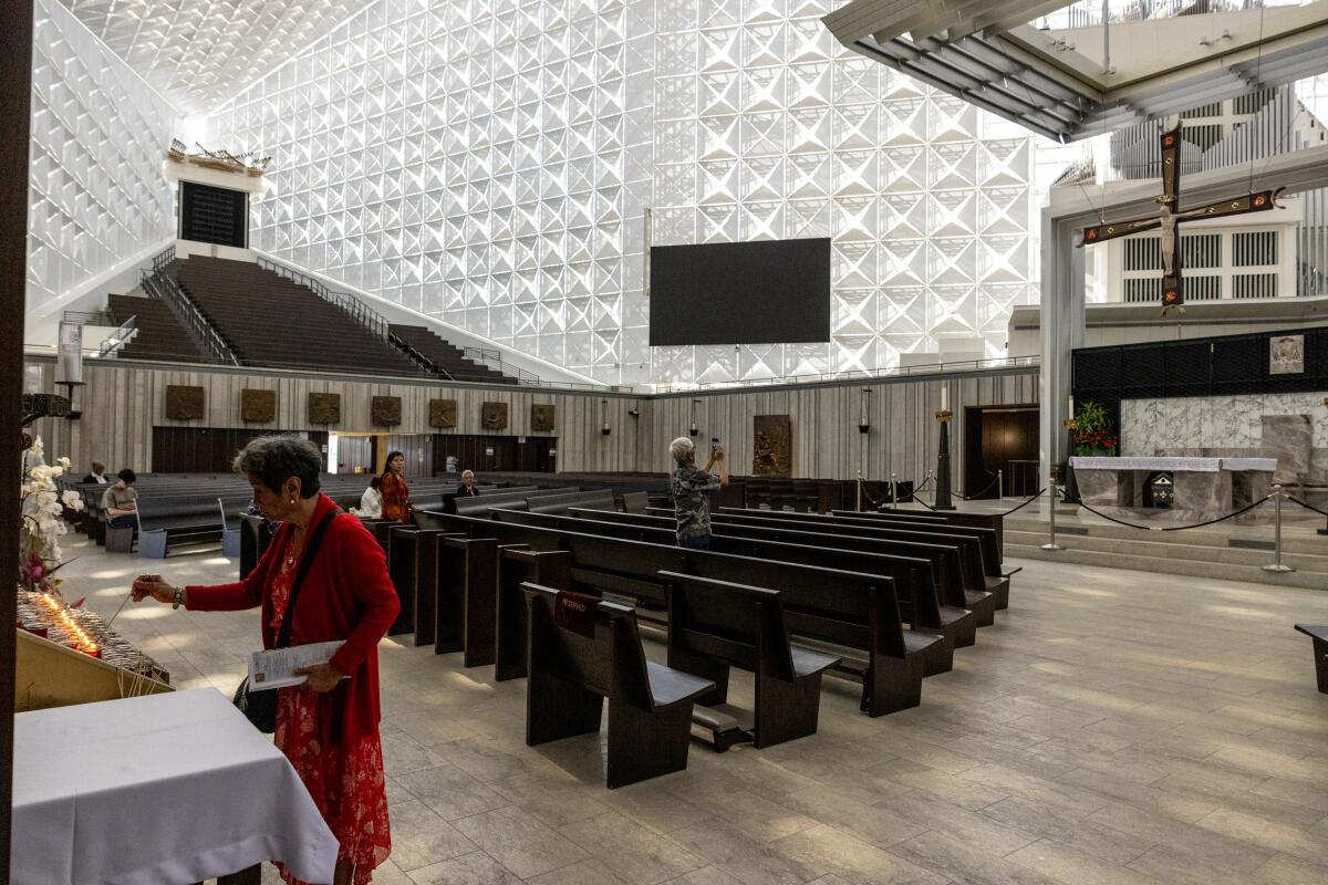 A woman lights a candle beside rows of pews inside the Christ Cathedral in Garden Grove.