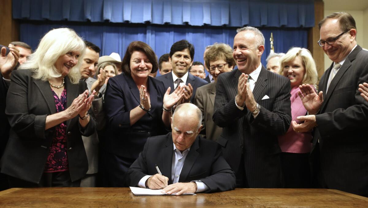 Gov. Jerry Brown receives applause from lawmakers as he signs a measure to place a $7.5 billion water plan on the November ballot on Aug. 13, 2014, in Sacramento. However, groundwater regulation is not included in the new water bond deal.