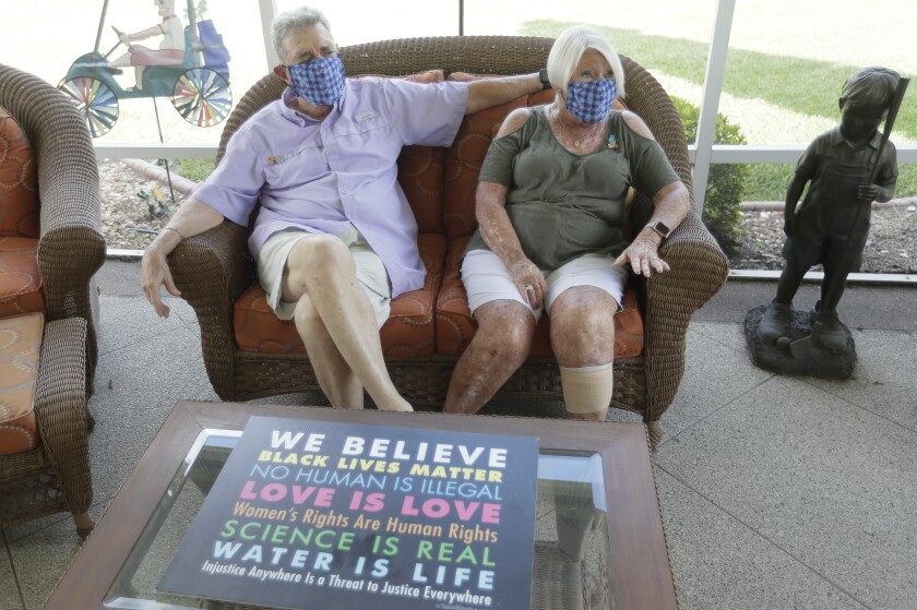 Ira and Ellen Friedman, wearing masks, sit outside their home at the Villages, Fla., retirement community.