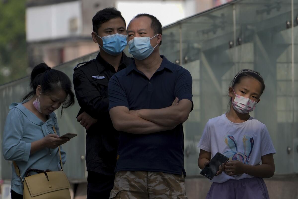 Personas con mascarillas hacen fila para recibir sus tests de rutina del COVID-19 en Beijing. 