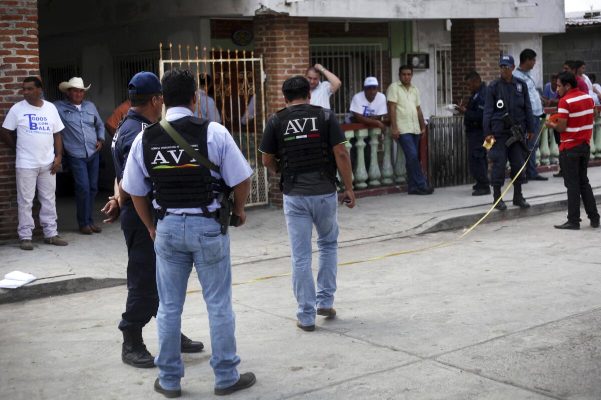 Police and forensics experts examine the scene outside the home of mayoral candidate Carlos Triana Garcia in Tlalixcoyan, Mexico, after gunmen opened fire on the home.