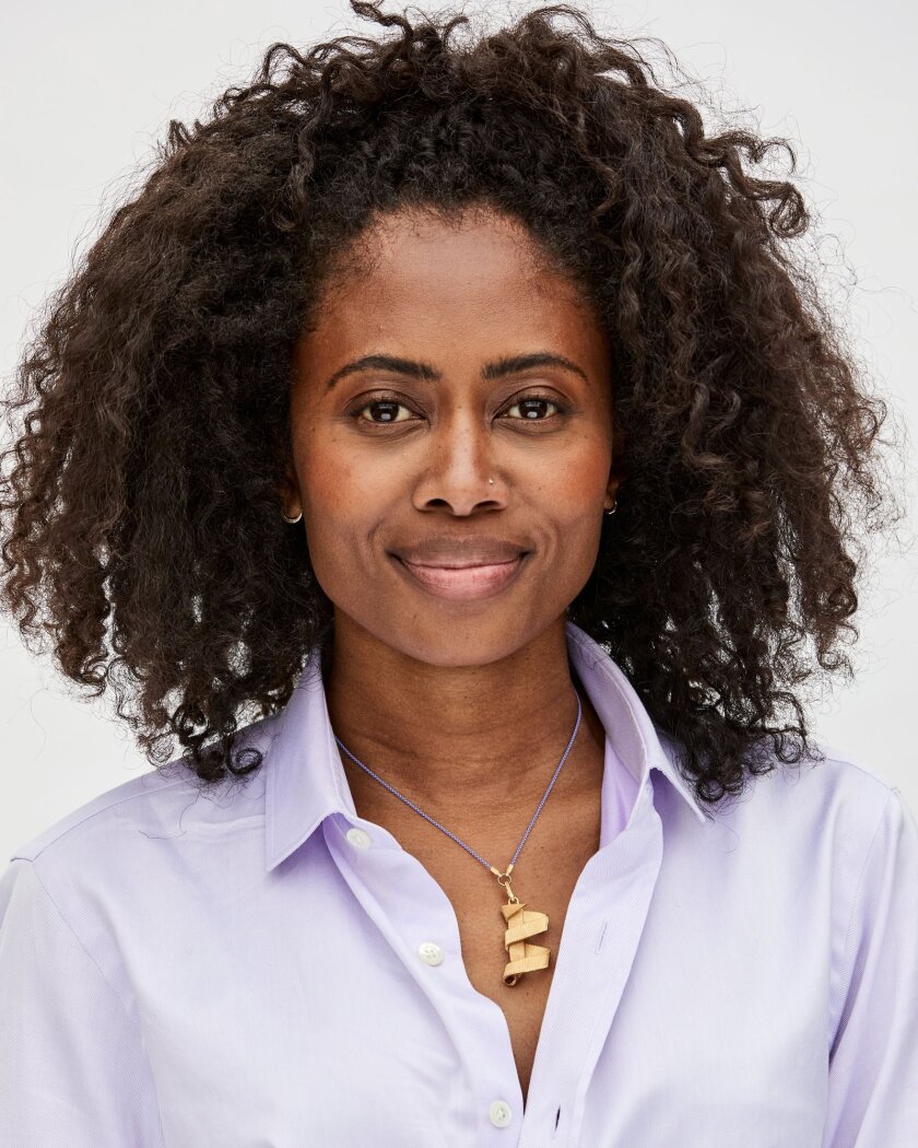 A woman wears a purple chain necklace with a charm