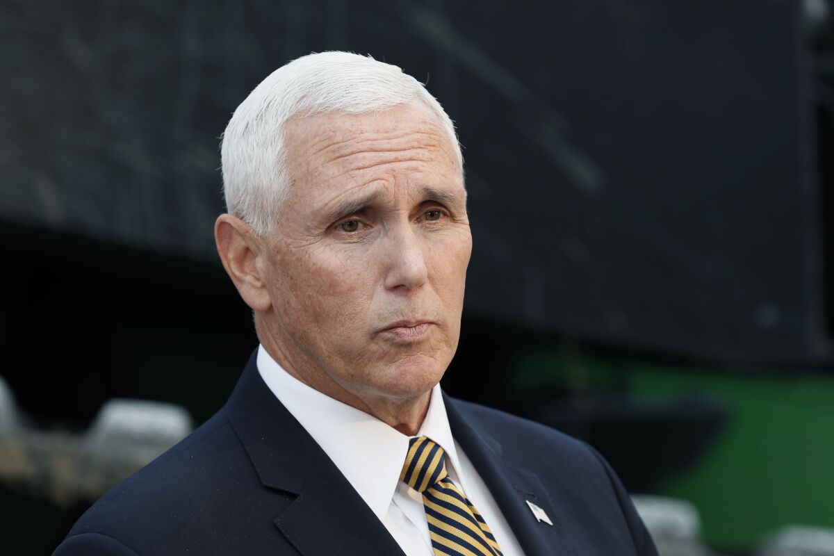 Mike Pence in blue suit and U.S. flag pin purses his lips.