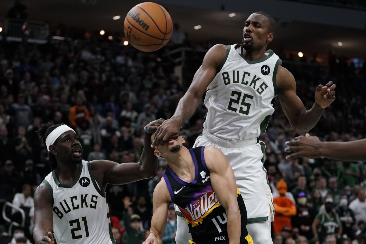 Phoenix Suns' Landry Shamet is fouled as he shoots between Milwaukee Bucks' Jrue Holiday (21) and Serge Ibaka (25) during the second half of an NBA basketball game Sunday, March 6, 2022, in Milwaukee. The Bucks won 132-122. (AP Photo/Morry Gash)