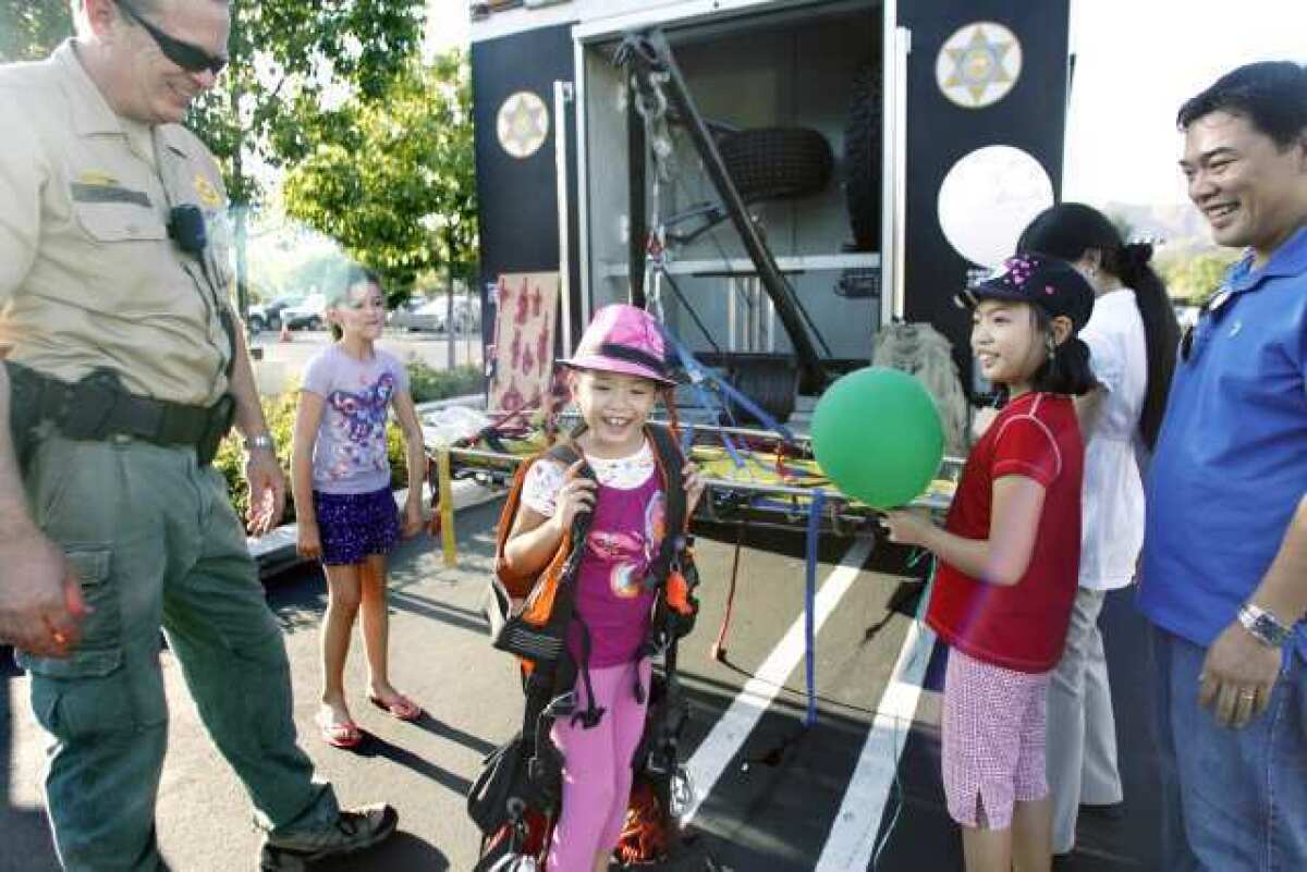 Angelica Aniciete, center, tries on a vest during National Night Out in La Canada on Tuesday.