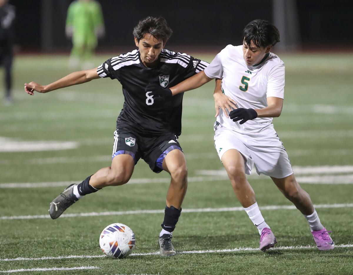 Costa Mesa's Carlos Alcala (8) and Saddleback's Jordi Quiroz (5) go shoulder to shoulder as they battle for ball control.