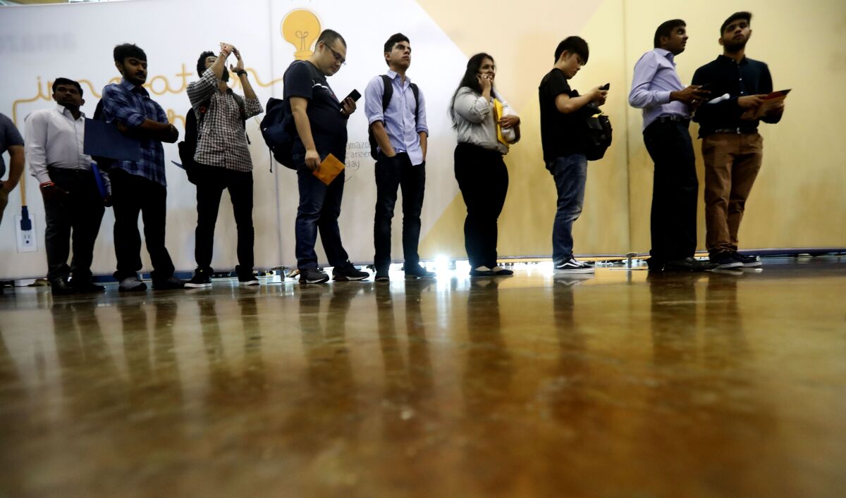 In this Sept. 17, 2019, photo job seekers line up to speak to recruiters during an Amazon job fair in Dallas. On Friday, Oct. 4, the U.S. government issues the September jobs report. (AP Photo/LM Otero)