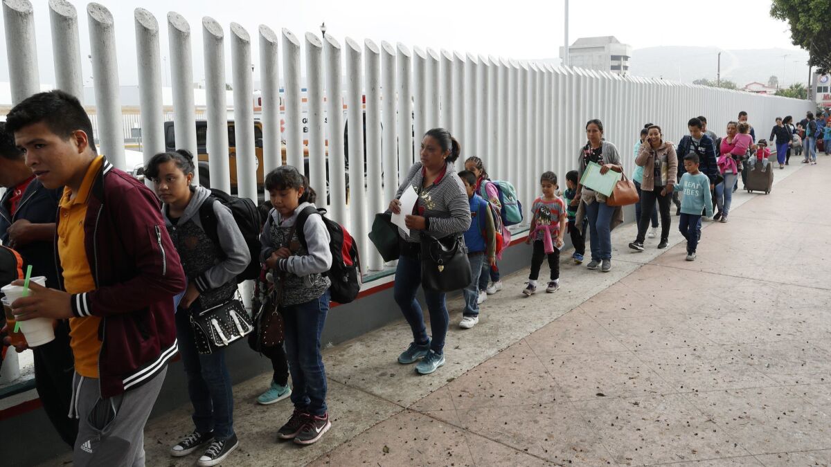 People line up to cross into the United States near the San Ysidro port of entry in Tijuana, Mexico, to begin the process of applying for asylum on July 26.