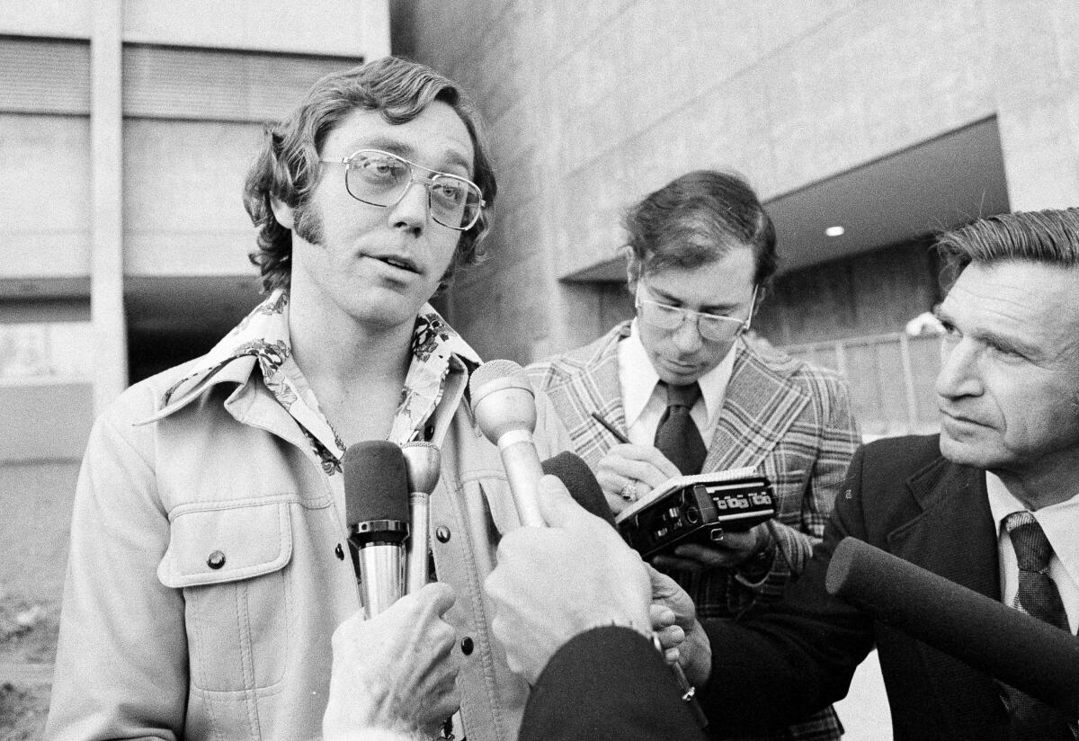 A man in glasses talks to reporters.