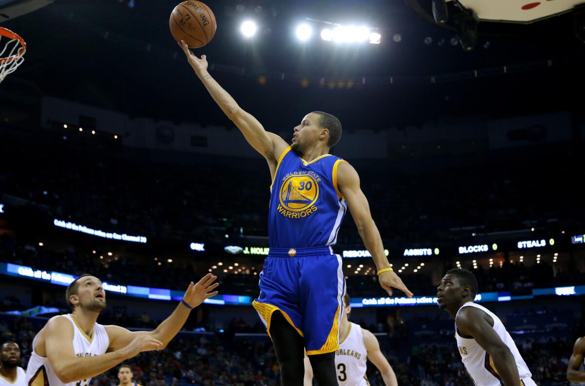 Warriors guard Stephen Curry glides over Pelicans defenders for a finger roll in Golden State's 16th straight win.