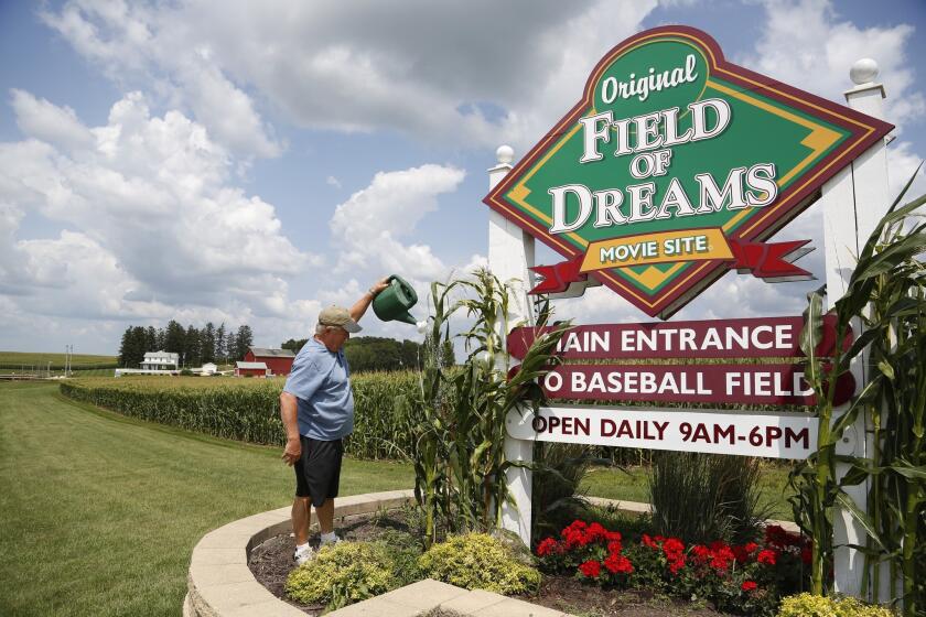 Former field co-owner Don Lansing waters the landscaping around the sign marking the entrance of the site in Dyersville, Iowa.