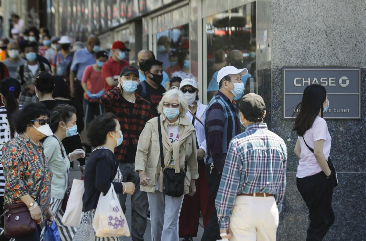 Clientes con cubrebocas esperan entrar a una sucursal del banco Chase, en el barrio de Queens de Nueva York. 