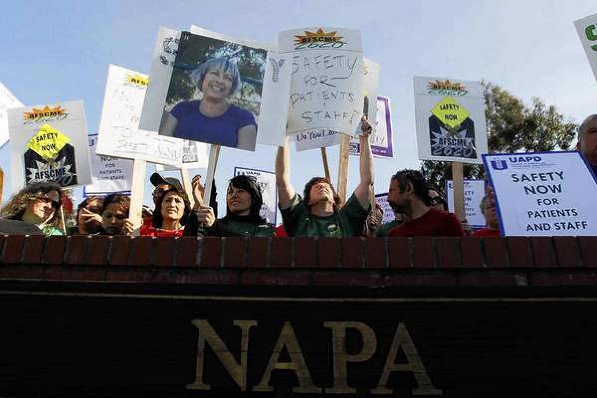 Employees at Napa State Hospital demonstrate for safer working conditions in 2011 after colleague Donna Gross, seen in the photo held aloft, was slain the year before by a patient. A now-required personal alarm on a lanyard was developed in response to the death.