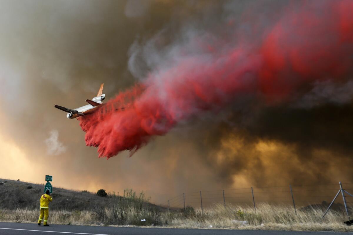 A DC-10 makes a fire retardant drop as the Anahiem Hills fire rages along Highway 241 and Santiago Canyon Road in Orange.