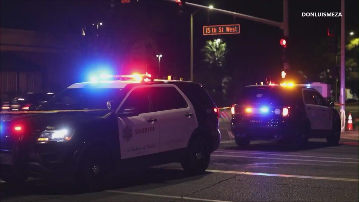 Two law enforcement SUVs are shown with their lights on at an intersection.