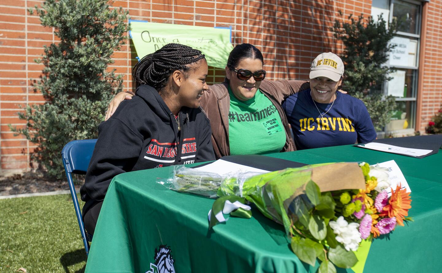 Lilia Mora, center, wraps her arms around her daugthers Felicia and Tayla Crenshaw during a signing day ceremony for the Costa Mesa High School throwing twins on Wednesday, April 25.