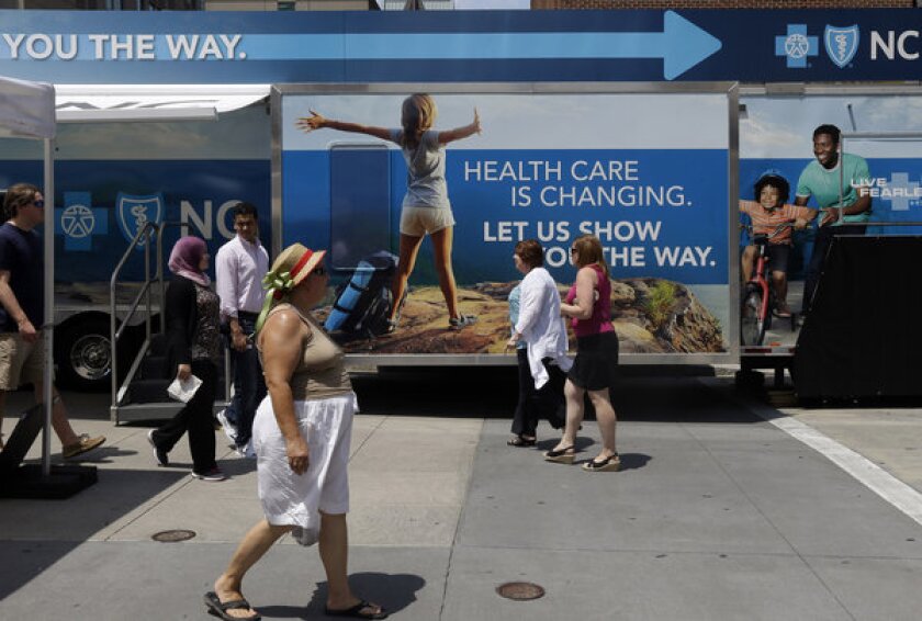 Pedestrians pass by a Blue Cross Blue Shield of North Carolina trailer in Raleigh, as the health insurance provider ramps up promotion in a changing healthcare landscape.