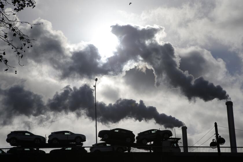 FILE - Smoke rises from a factory as a truck loaded with cars crosses a bridge in Paris, on Nov. 30, 2018. President Emmanuel Macron is to unveil France's approach and means to meet its climate-related commitments within the next seven years as a special government meeting is taking place on Monday Sept. 25, 2023. (AP Photo/Michel Euler, File)
