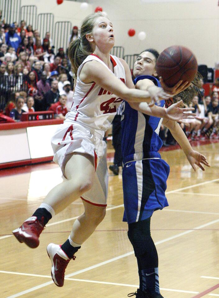 Burroughs' Brooke Radcliff drives for a layup and is fouled by Burbank's Sharis Ghazeri in a Pacific League girls basketball game at Burroughs High School on Thursday, February 13, 2014.