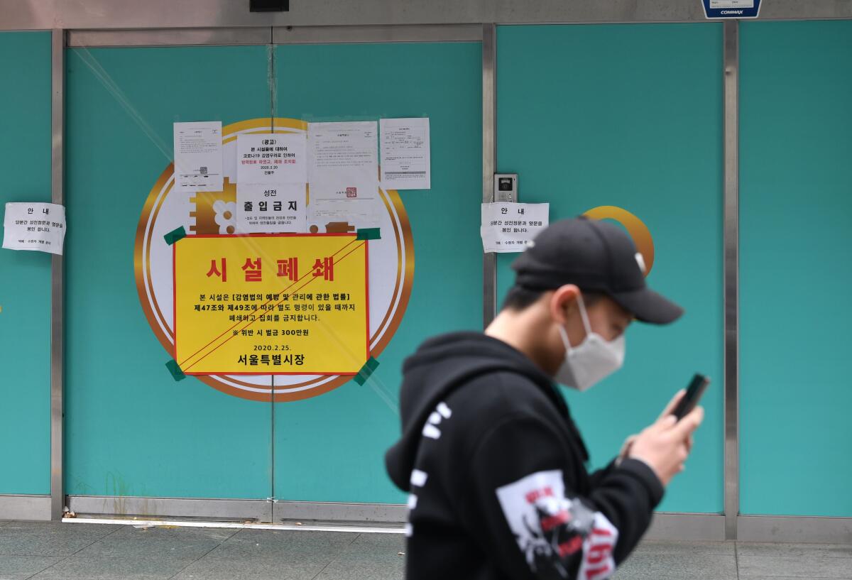 A man wearing a face mask walks past a branch of the Shincheonji Church of Jesus, which was temporarily closed by South Korea to help prevent the spread of the COVID-19 coronavirus.