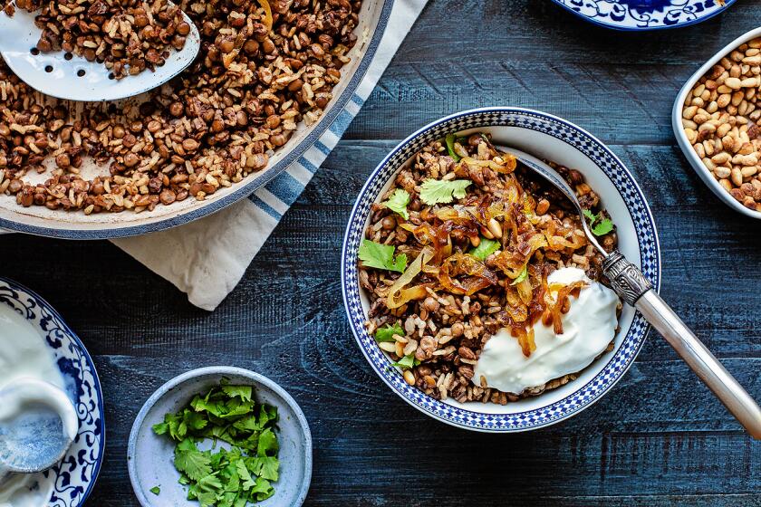 A bowl of rice and lentils topped with caramelized onions and a dollop of yogurt.