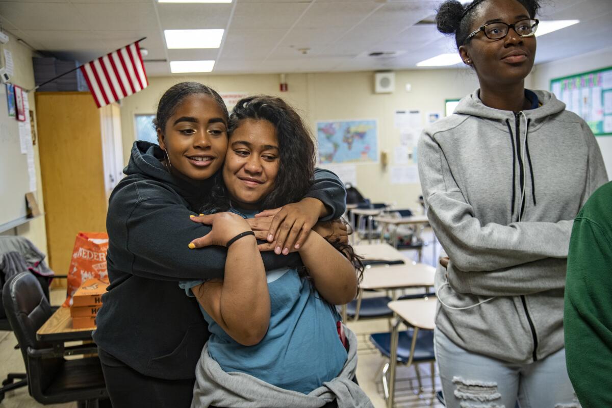 Nia Burton, 17, left, hugs Ananaiah Fiaseu, 17, as they wait to hear if their essay will be chosen to receive free prom dresses. Chioma Nzeogu, 18, of Compton, right, was the first winner.