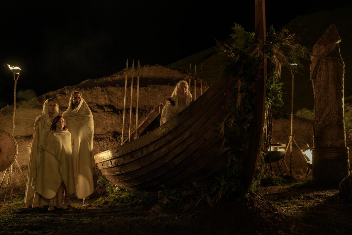 Actors stand near a boat in a scene from "The Northman."