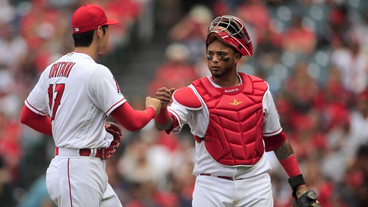 Angels starting pitcher Shohei Ohtani fist-bumps with catcher Martin Maldonado after finishing the third inning against the Tampa Bay Rays at Angel Stadium.
