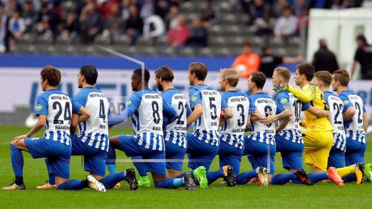Players of Hertha Berlin kneel down prior to the German Bundesliga soccer match.