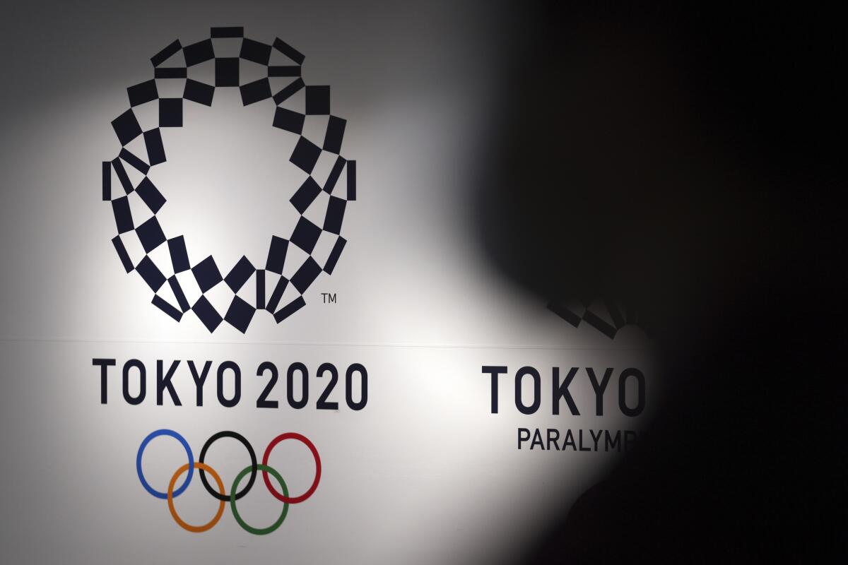 Una persona pasa frente al logo de Tokio 2020 en el Aeropuerto de Haneda, Tokio, 14 de junio de 2021. 