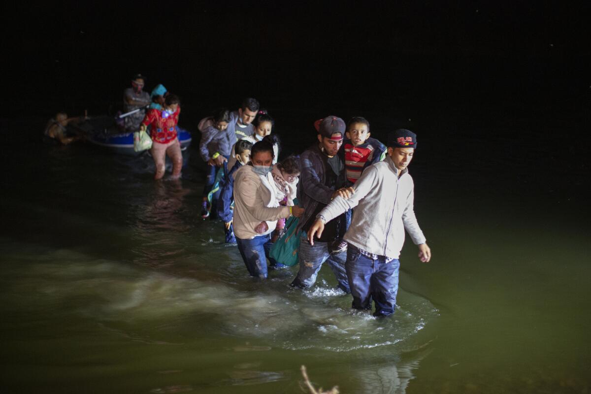 Migrant families wade through a body of water