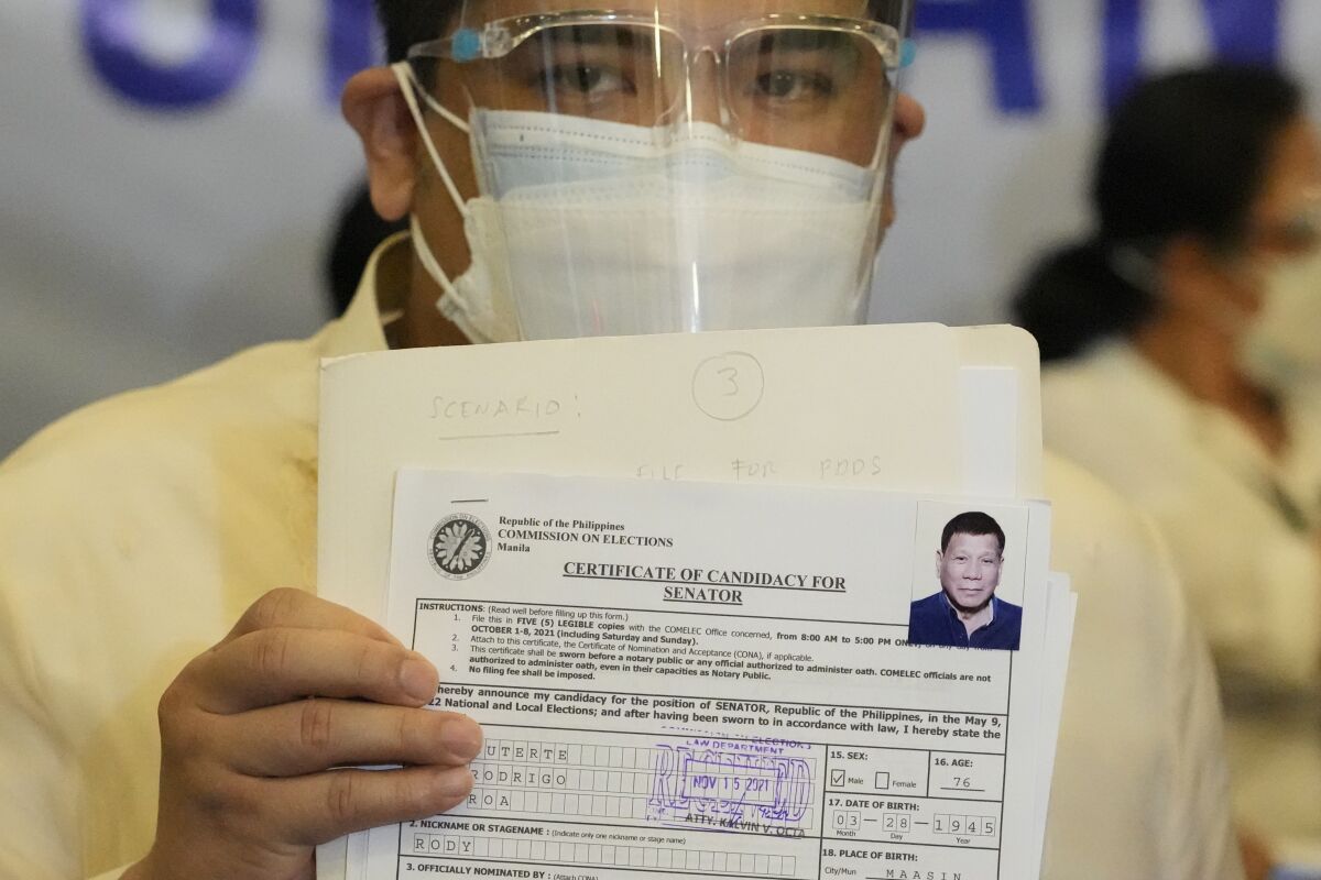 A representative of Philippine President Rodrigo Duterte holds his Certificate of Candidacy for Senator at the Commission on Elections in Manila, Philippines, Monday, Nov. 15, 2021. Duterte filed his candidacy Monday for a Senate seat in next year's elections, walking back on his announcement that he would retire from politics when his term ends and prompting human rights activists to press allegations that he would do anything to cling to power to evade accountability for his deadly anti-drugs crackdown. (AP Photo/Aaron Favila)