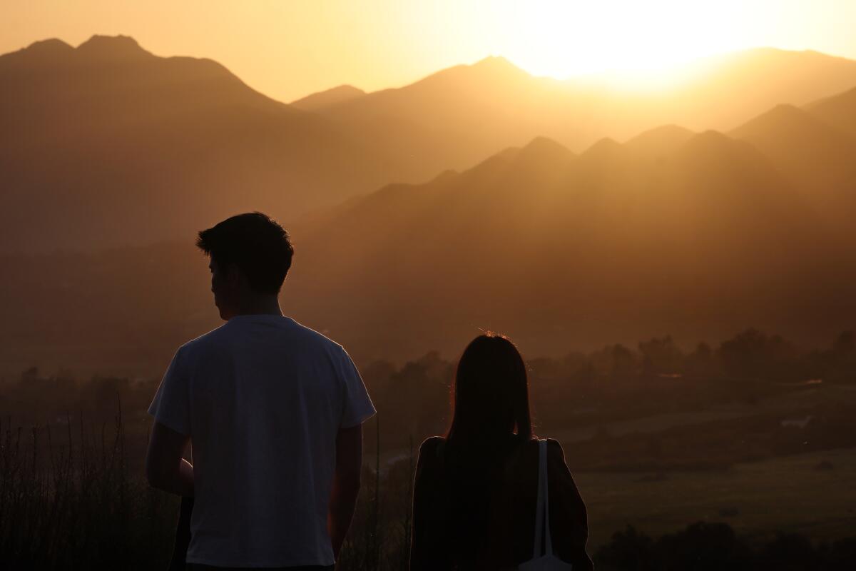 Two people watch the sunset.