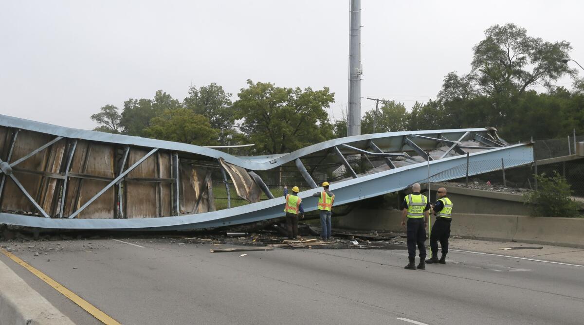 Investigators look over the scene of a collapsed pedestrian bridge over the Southfield freeway Friday in Detroit.