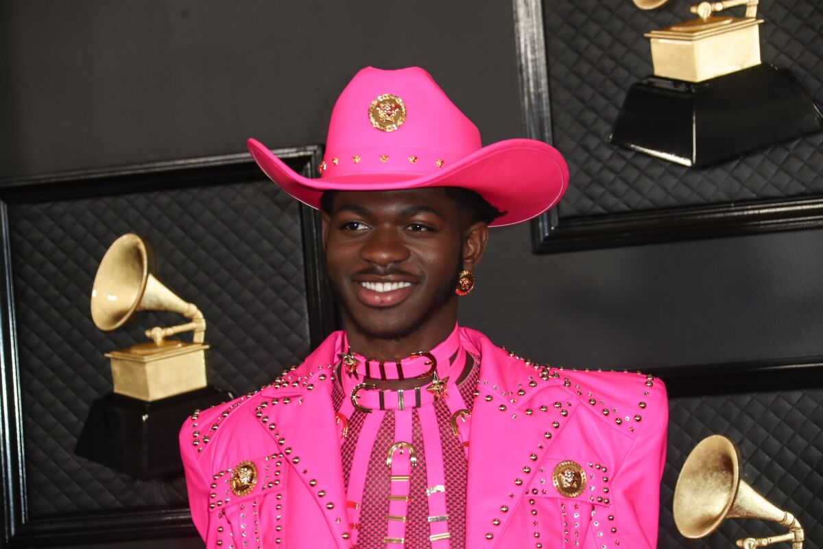 A man posing in a hot pink cowboy suit and hat