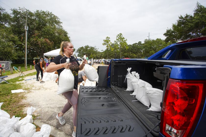 Victoria Colson, 31, of Tampa loads sandbags into her truck along with other Tampa residents who waited for over 2 hours at Himes Avenue Complex to fill their 10 free sandbags on Sunday, Sept. 25, 2022, in Tampa, Fla. (Luis Santana/Tampa Bay Times via AP)