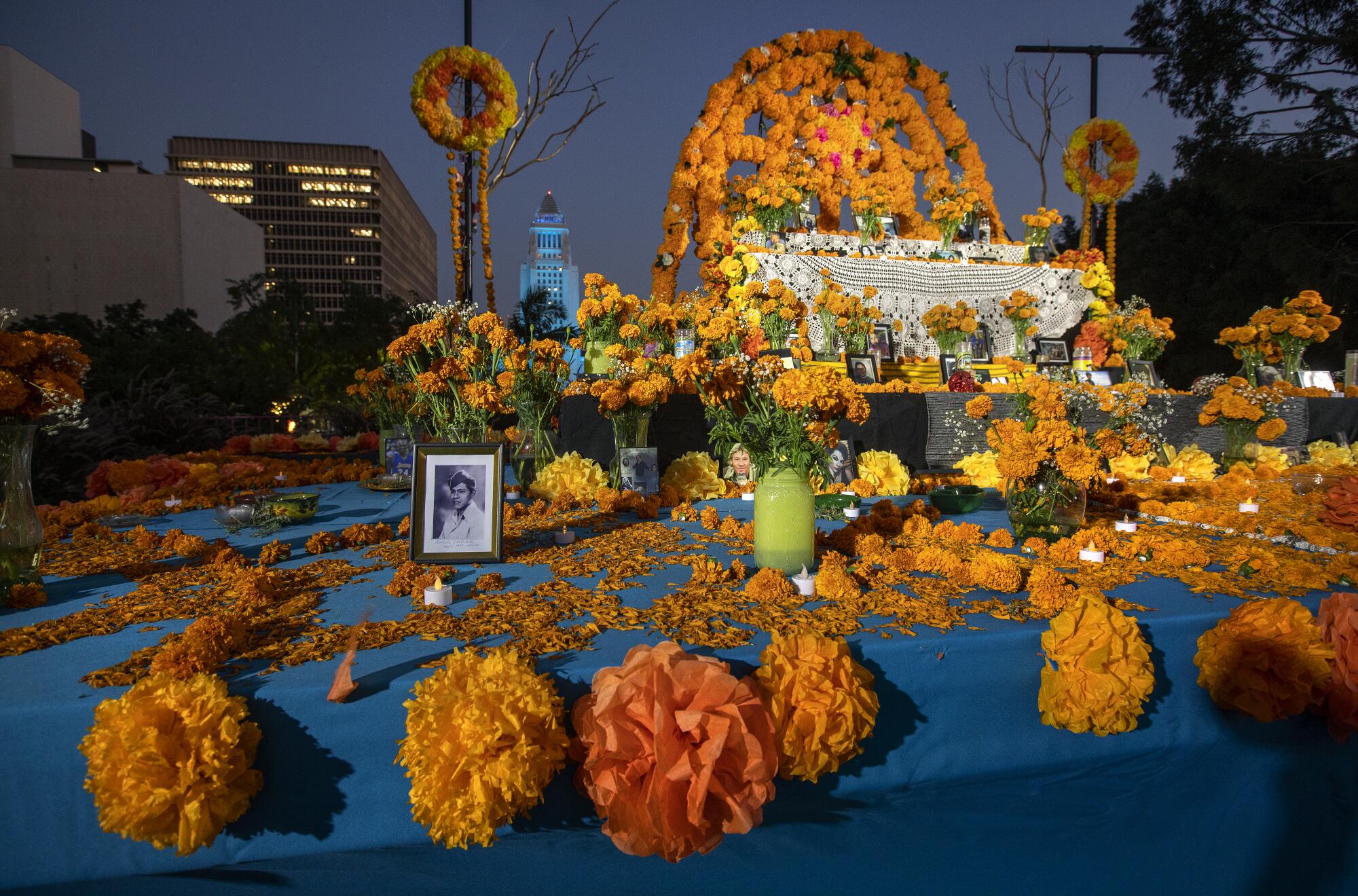 The orange flowers, photos and candles of the community altar are seen at dusk.