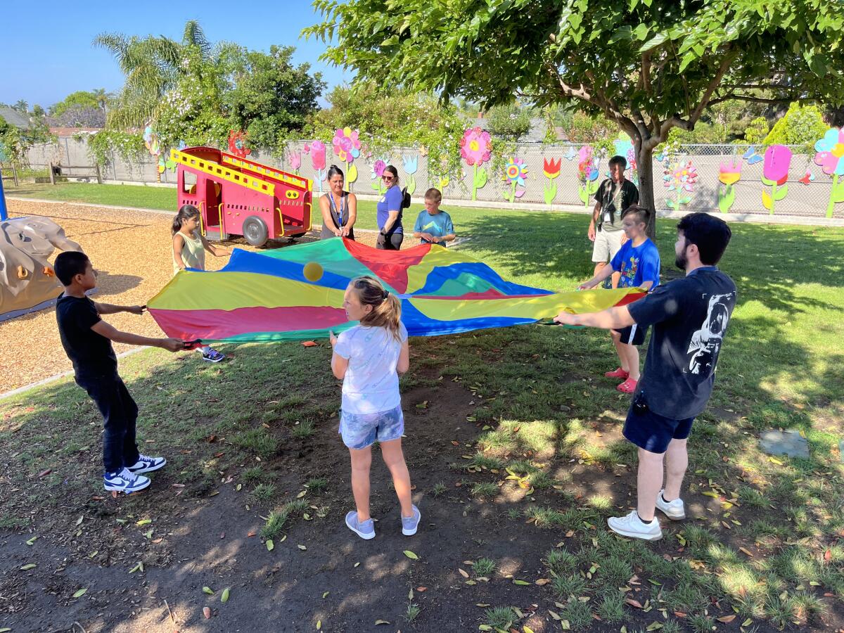 Children waving a rainbow parachute.
