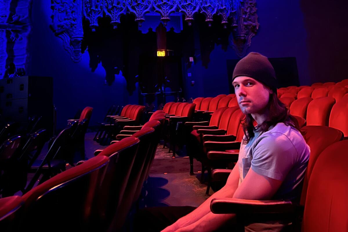 A man sits in a darkened theater bathed in red light