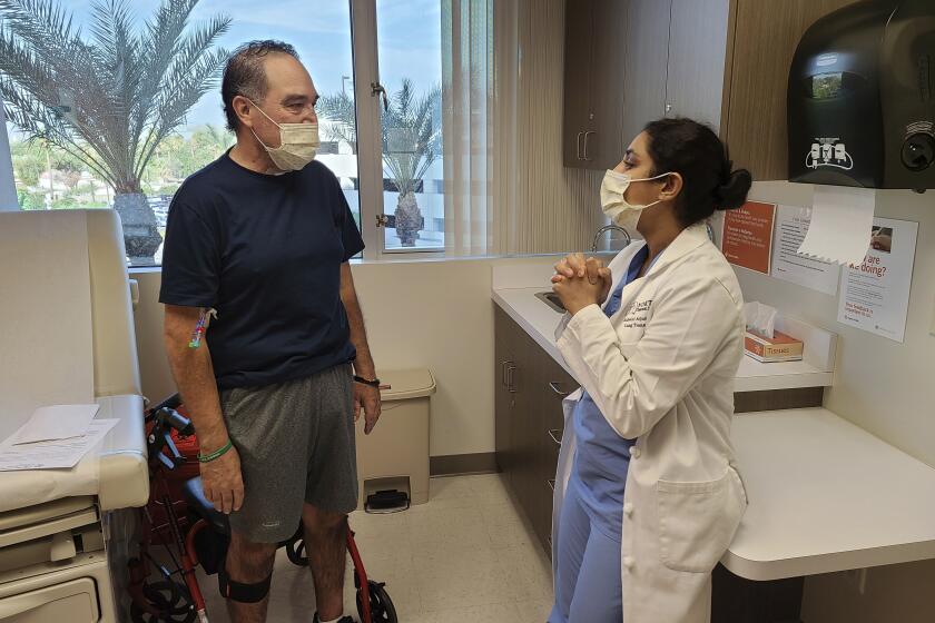 In this photo provided by Dignity Health St. Joseph's Hospital, Arthur Sanchez, left, speaks with Dr. Ashwini Arjuna during a follow-up appointment, post-transplant, at St. Joseph's Hospital in Phoenix, Wednesday, Oct. 21, 2020. Seven months after he was first hospitalized in his hometown of Las Cruces, New Mexico, with COVID-19, the 52-year-old utility worker has a brand new set of lungs. (Courtesy of Dignity Health St. Joseph's Hospital via AP)