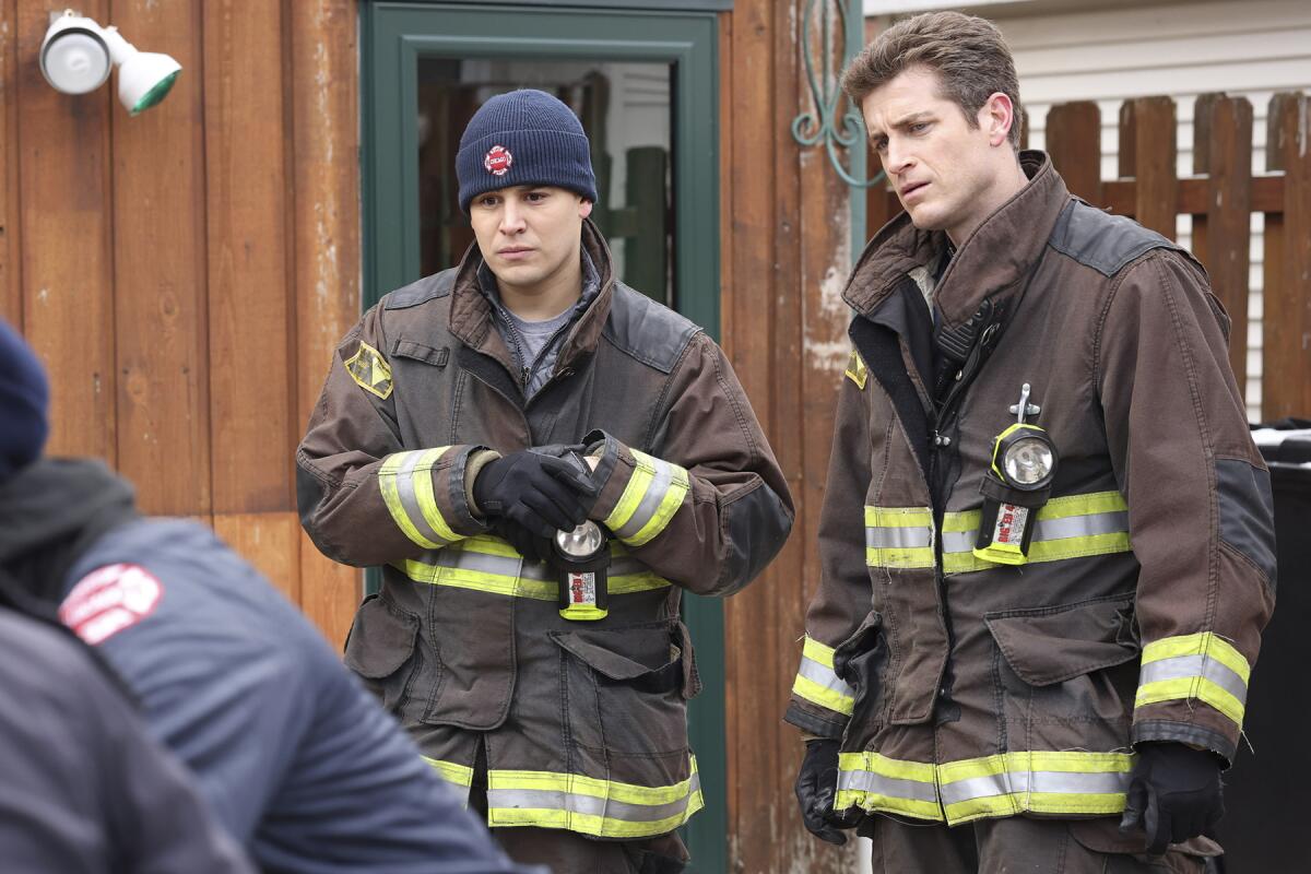 Two people in firefighting gear stand side by side.