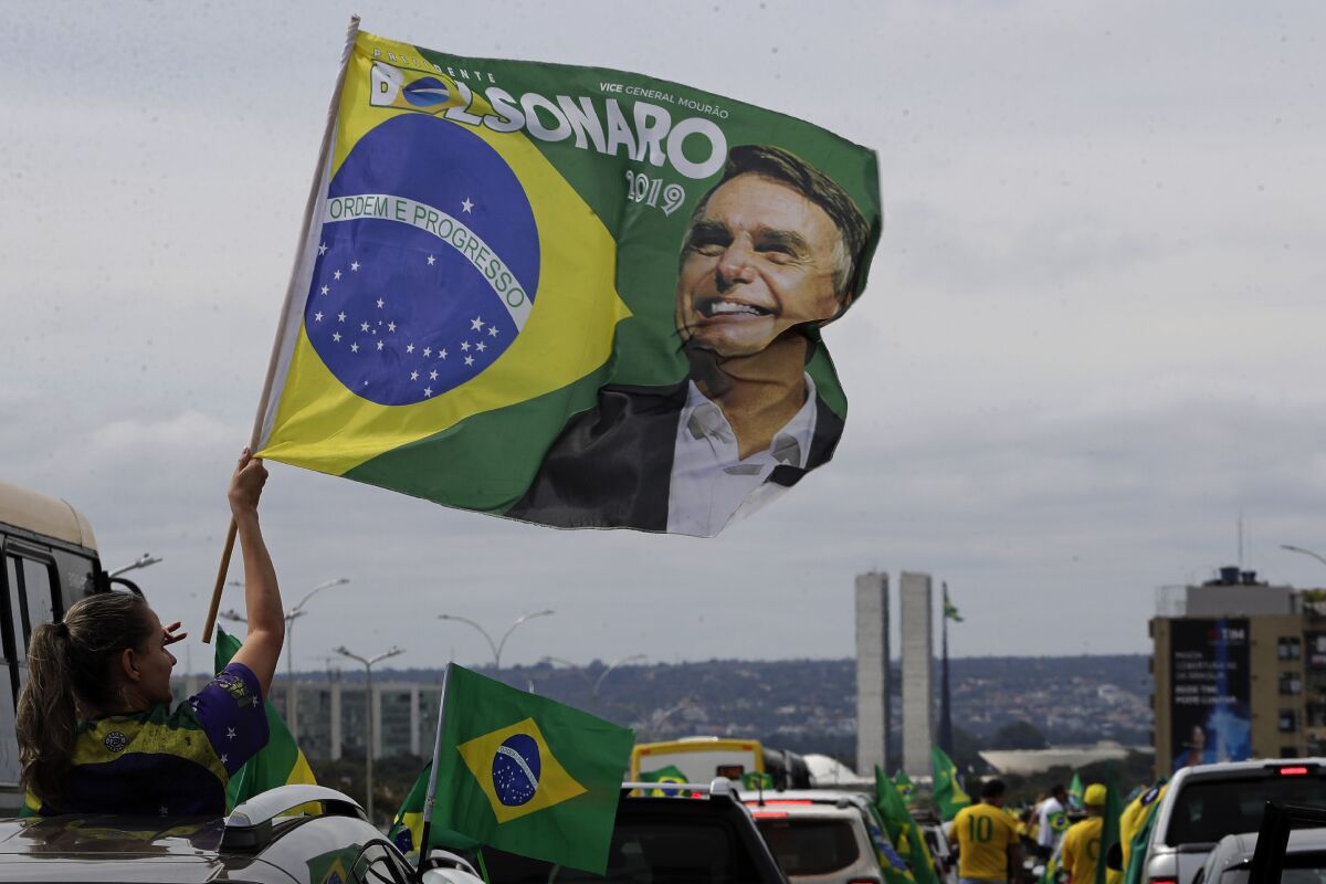 A demonstrator waves a banner with an image of President Jair Bolsonaro, during a caravan backing Bolsonaro’s anti-coronavirus-lockdown stance, marking May Day, or International Workers' Day, in Brasilia, Brazil, Saturday, May 1, 2021. (AP Photo/Eraldo Peres)