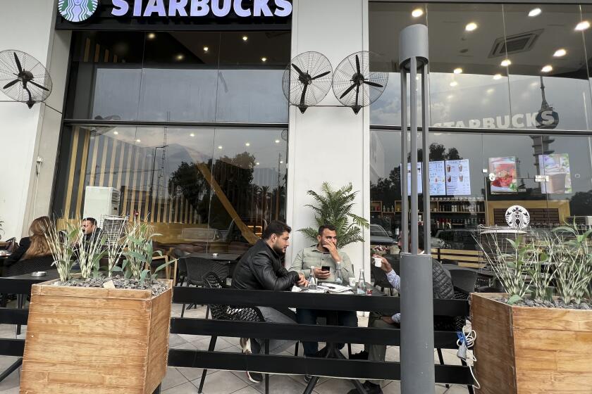 People sit in an unlicensed Starbucks cafe in Baghdad, Iraq, Wednesday, Dec. 21, 2022. Real Starbucks merchandise is imported from neighboring countries to stock the three cafes in the city, but all are unlicensed. Starbucks filed a lawsuit in an attempt to shut down the trademark violation but the case was shuttered after the owner allegedly threatened lawyers hired by the coffee house. (AP Photo/Ali Abdul Hassan)