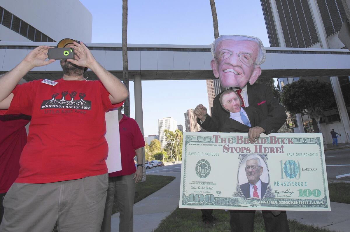 Teachers rally against a charter school proposal Tuesday. One demonstrator wears an oversized Eli Broad mask while carrying a doll in the likeness of former Supt. John Deasy.