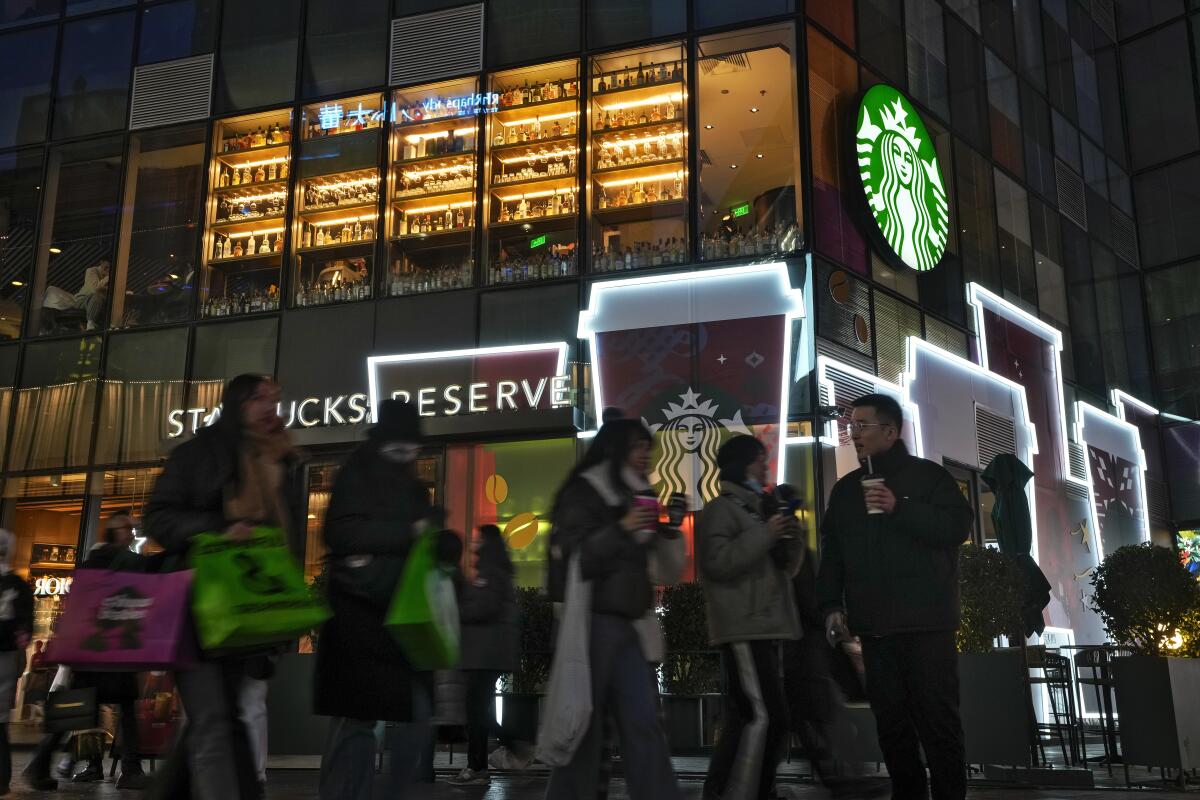 Shoppers walk by a Starbucks cafe at an outdoor shopping mall in Beijing.