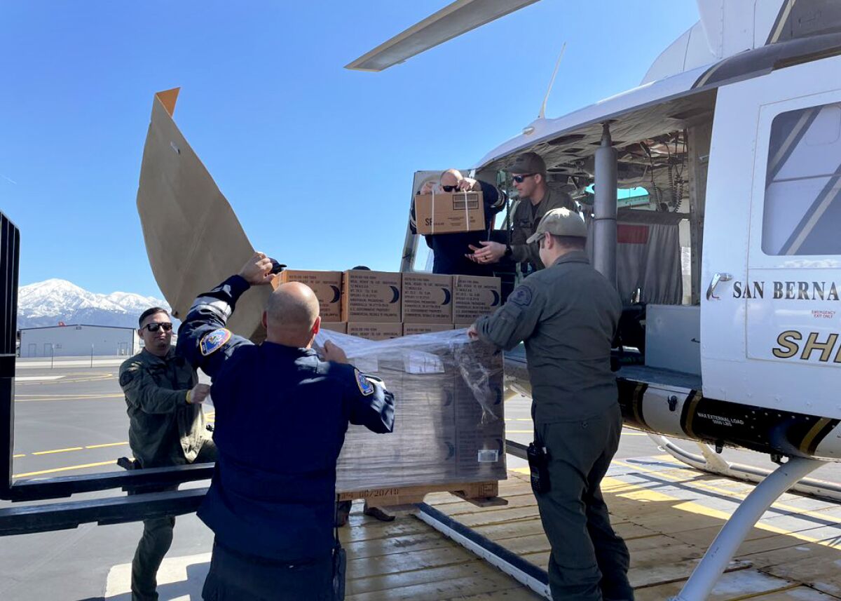 Emergency personnel load boxes onto a helicopter.